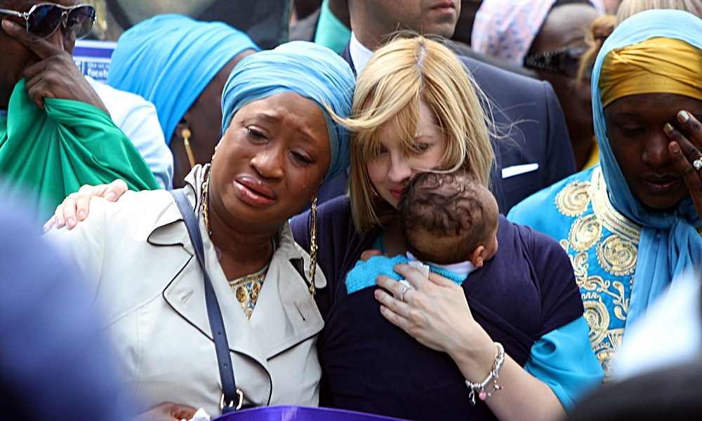 Sheku's partner Collette Bell and their baby Isaac with other grieving mourners at Mr Bayoh's funeral.