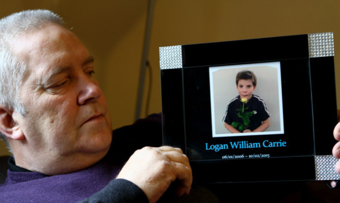 Robert Brown holds a photo of his grandson Logan.