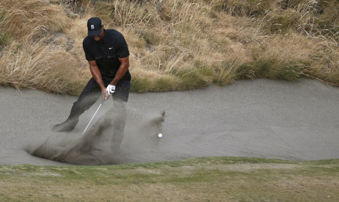 Tiger Woods hits out of the bunker on the 10th hole during the first round.