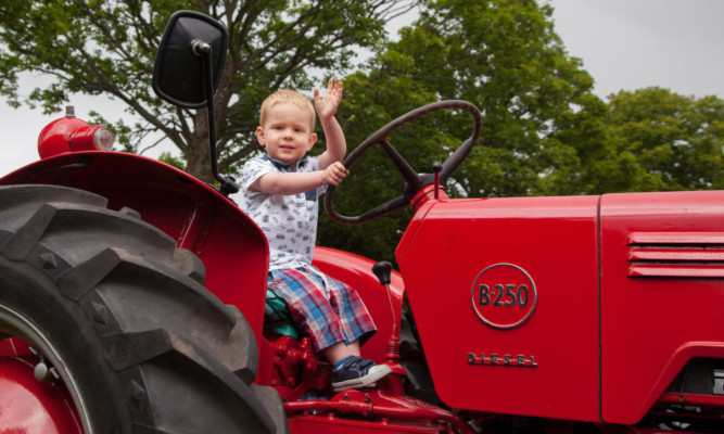 Two-year-old Jack Winstanley tries out a vintage tractor.