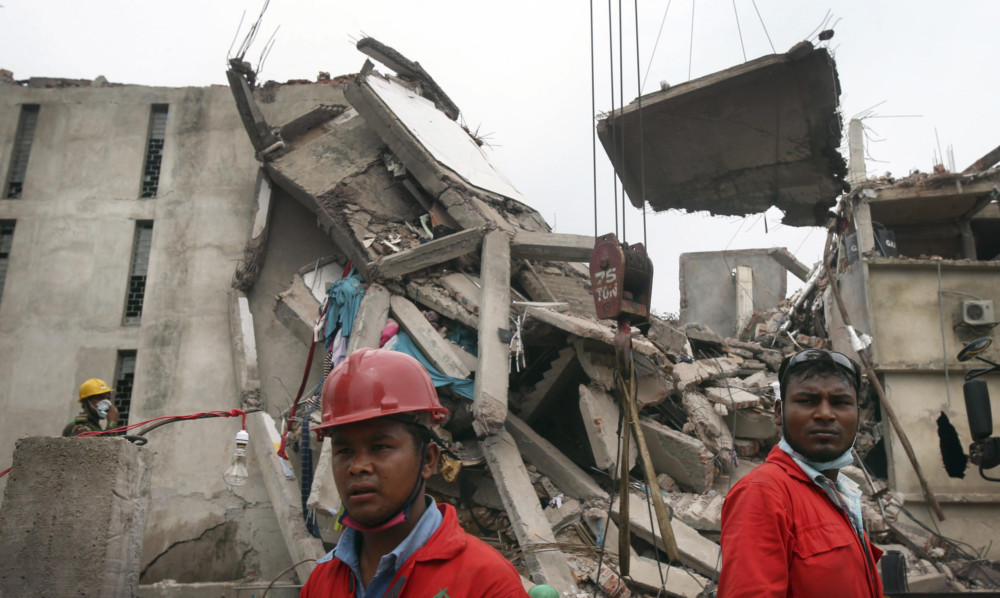 Workers watch as a crane lowers the ceiling of the garment factory building which collapsed in Savar, Bangladesh.