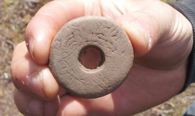 The spindle whorl was used while hand spinning textiles to maintain the speed of the spin.