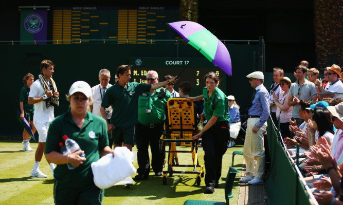 A ball boy receives medical attention after collapsing on court 17 at Wimbledon.