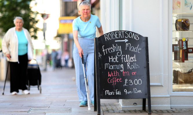 Sandra Wilson, who is registered blind, finding her way around an advertising board on Kirkcaldy High Street.
