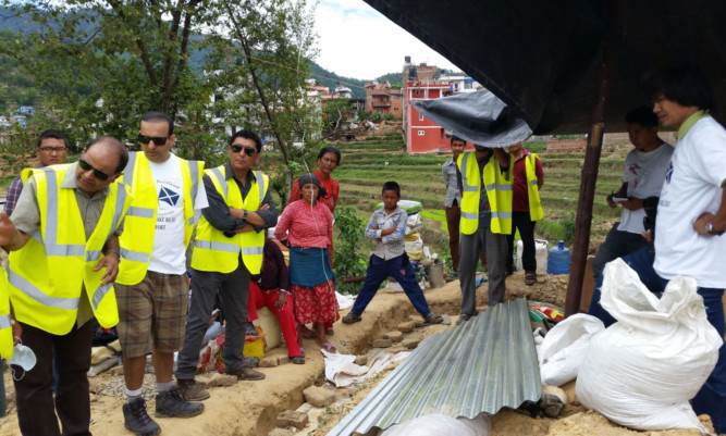 Mr Khanal, left, overseeing the construction of a temporary house in Nepal.