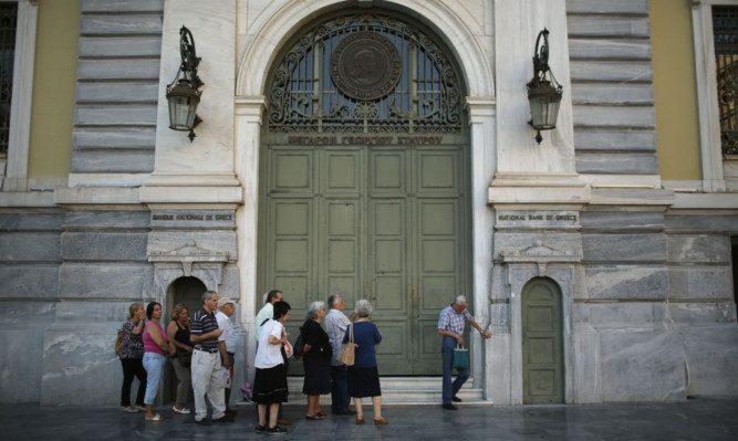 Senior citizens queue up to collect their pensions outside a National Bank of Greece branch in Kotzia Square in Athens.