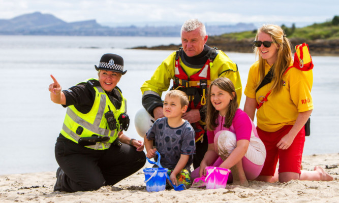 Six-year-old Zac Williams, front left, and sister Leni Williams, 9, alongside Community Ward Officer PC Kate Blackwell, watch manager Gerry Walkingshaw of the Water Rescue Unit and RNLI lifeguard Kayleigh Reid.