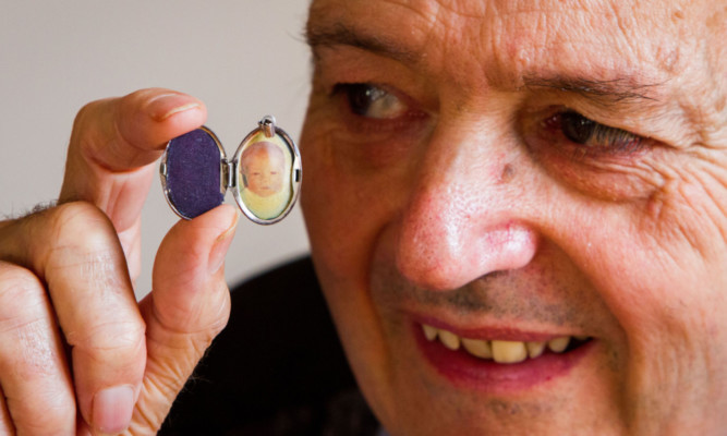 Michael Mulford with the locket containing a photograph of a baby.