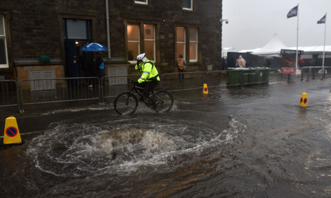 Security staff ride through standing water outside St Andrews, Fife.