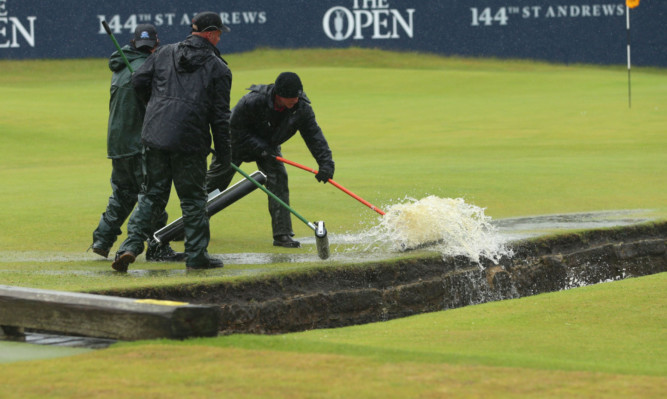 Greens staff clearing water from the 18th tee area this morning.