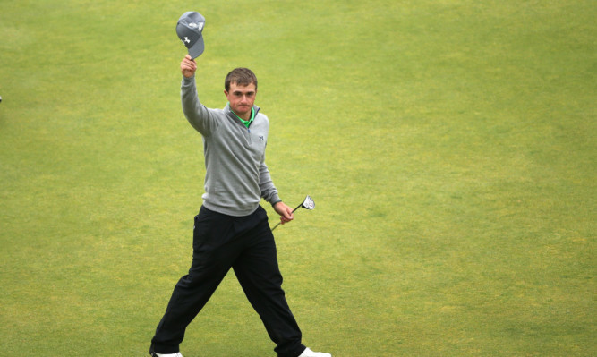 Amateur Paul Dunne waves to the crowd on 18th green.