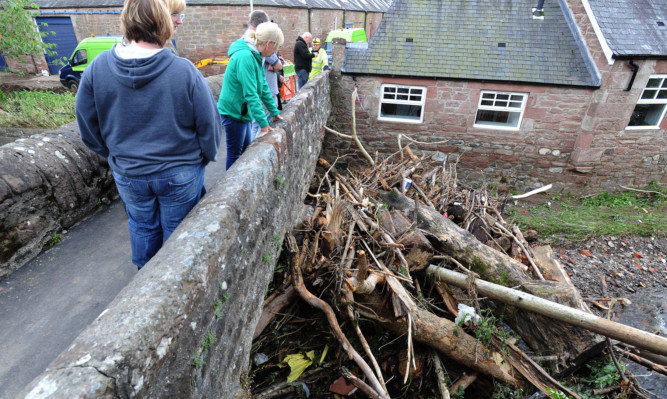 Locals viewing the debris washed down and caught on the Pack Bridge last week.
