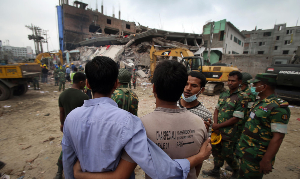 Grieving onlookers comfort each other while workers toil in the collapsed garment factory.