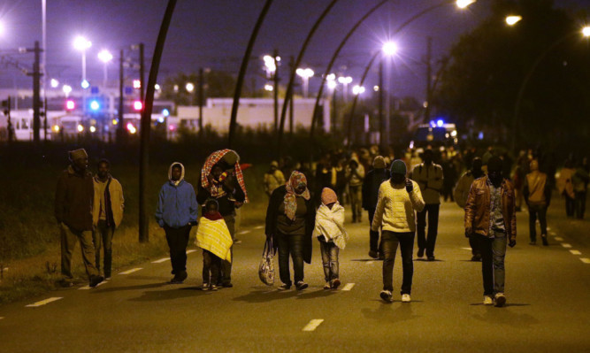 Migrants, including young children, are moved away from the perimeter fence of the Eurotunnel site at Coquelles in Calais.