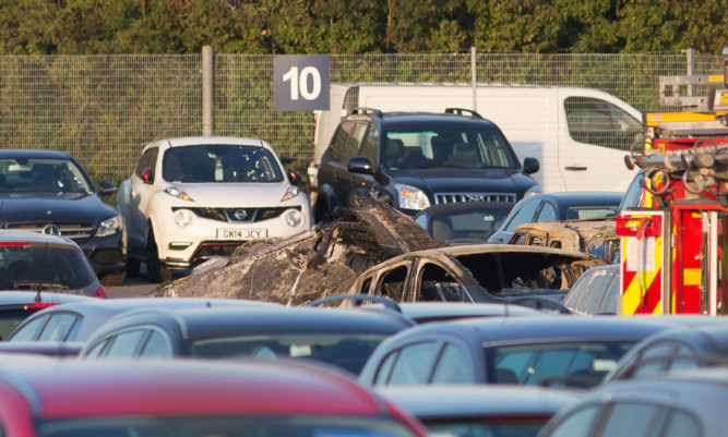 The scene of the crash as four people have died after a private jet crash-landed in a car auction site and burst into flames as it approached the runway at Blackbushe Airport in Hampshire.