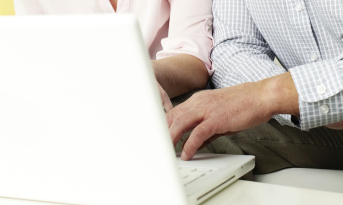 Portrait of mature man and his wife working with laptop at home