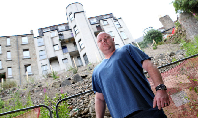 David beside the scene of the landslide at his property and, below, with one of the boulders that rolled down the hill and struck his home.