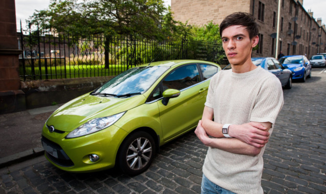 Steven with his car, which was scratched so badly by vandals that he thinks it will cost around £1,000 to repair.