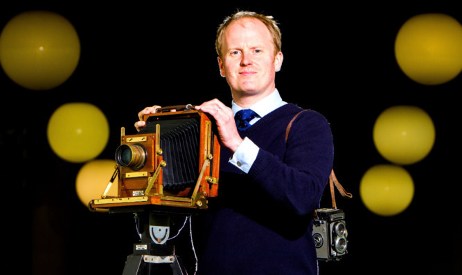 auctioneer Nick Burns with an American optical large format camera on a tripod.