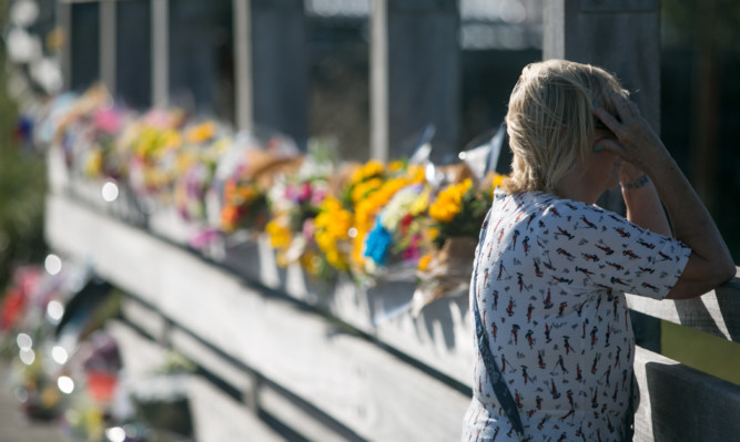 A woman pauses to reflect near floral tributes to the Shoreham Airshow crash victims.