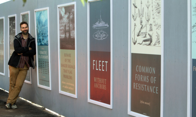 Artist Owen Daily beside some of the posters on display at the back of the Caird Hall.