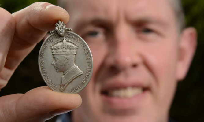 David Wallace shows the Second World War medal that he found with his metal detector.