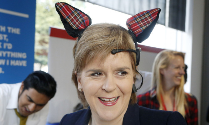 Nicola Sturgeon puts on an electroencephalogram with tartan ears during a visit to the Prince's Trust Wolfson Centre in Glasgow.