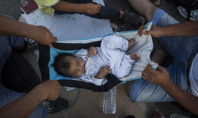 Refugees who have made it to the Greek island of Lesbos playing with a baby as they await transport to Athens.