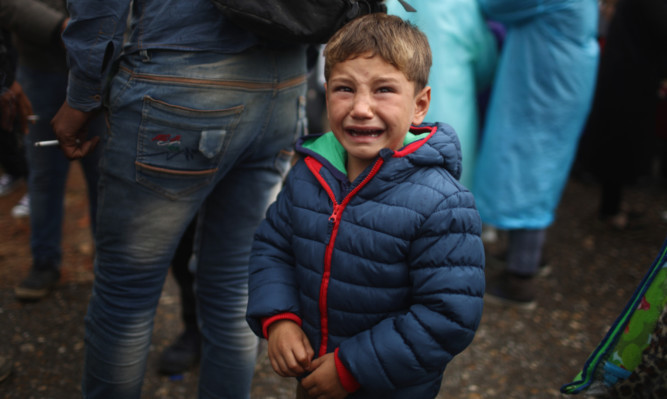 A young migrant boy cries from the cold and rain as he and his family make their way through Serbia towards Hungary.