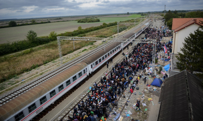 Syrian refugees wait at a train station in Tovarnic in Croatia to board a train heading towards the Austria.