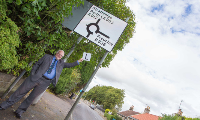 Cllr David McDairmid at the mis-spelt signage in Falkland just outside the primary school.