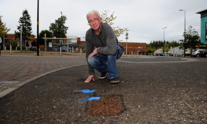 Jim Bryce beside one of the drain access points which were choked with syringes.