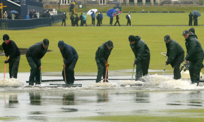 Green keepers clearing the Old Course after heavy down pours during The Open