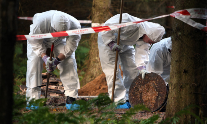 Forensics officers inspecting the area around the fire-ravaged lodge.