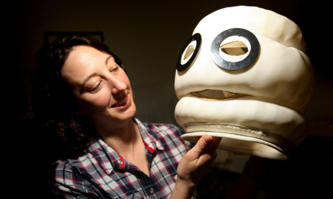 conservator Rebecca Jackson-Hunt gets to grips with the head of a Michelin Man suit.