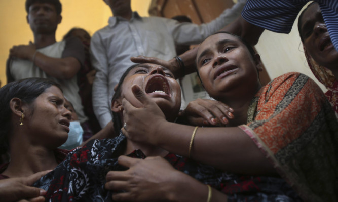 A woman is comforted after the body of a relative is recovered from the destroyed factory.