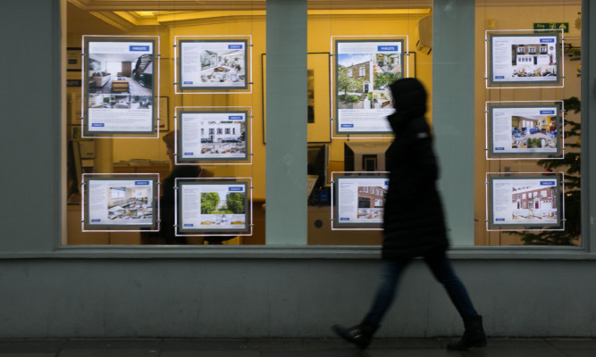 04/12/14 PA File Photo of a pedestrian walking past an estate agents in South Kensington, London. See PA Feature FINANCE Property Prices. Picture credit should read: Daniel Leal-Olivas/PA Photos. WARNING: This picture must only be used to accompany PA Feature FINANCE Property Prices