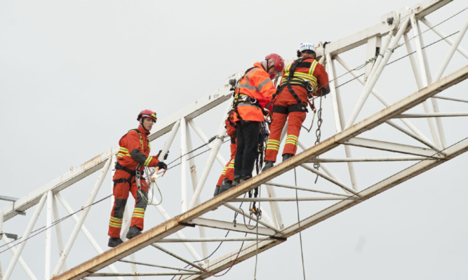 Firefighters escort Mr Lynch to safety from the crane.