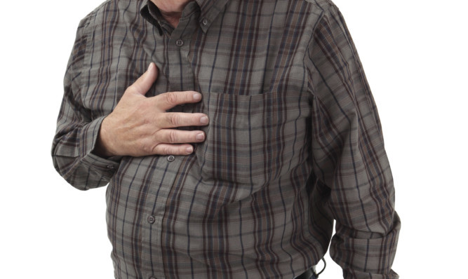 Photo of a man in his sixties suffering pain from a heart attack or severe indigestion.