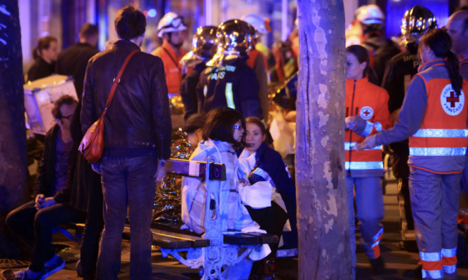 People rest on a bench after being evacuated from the Bataclan theater.