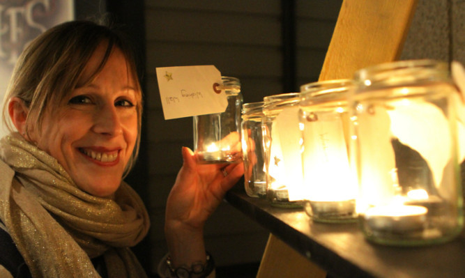 Project manager Claire Dow placing a candle on the wall.