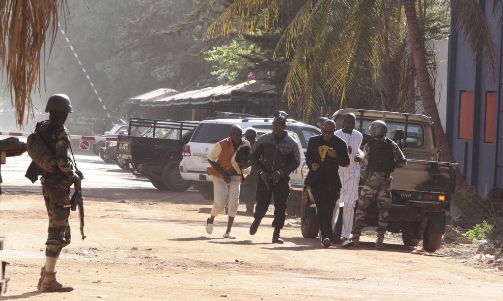 People run to flee from the Radisson Blu Hotel in Bamako, Mali, Friday, Nov. 20, 2015. The company that runs the Radisson Blu Hotel in Mali's capital says assailants have takenhostages in a brazen assault involving grenades. (AP Photo/Harouna Traore)