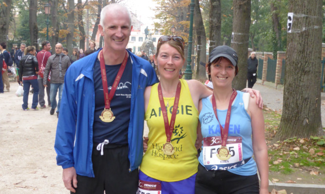 Angie Mackenzie, centre, with husband Hugh and friend Karen Fletcher at the Venice Marathon finish line.