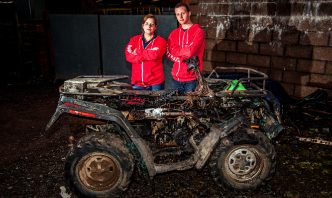 Pam Drew and Paul Marriott beside the burnt-out wreck.