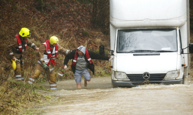 A man is helped out of his van after the River Teviot in Hawick broke its banks. The Borders and northern England were worst hit on Saturday.