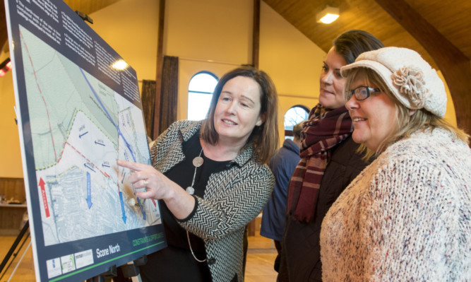 Emelda  MacLean, planning consultant from Emac planning, shows the plans to locals Lee Trussell and Jackie Elliott.