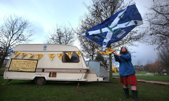 Gail Miller waves a Saltire flag next to her caravan at the independence camp nea the Scottish Parliament in Edinburgh.