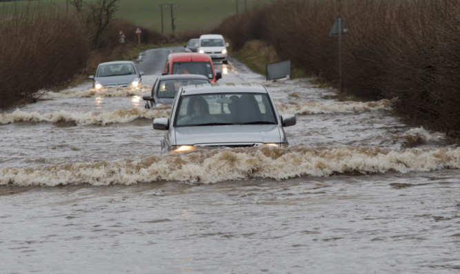 Motorists push their way through a flooded road near Coupar Angus.