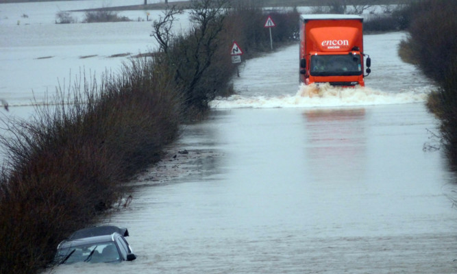 The lorry driver approaches the car that was abandoned in the floodwater on Sunday.