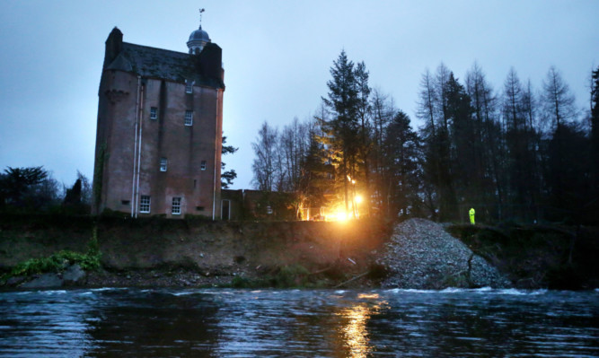 Rocks are moved into position by trucks on the shoreline at Abergeldie Castle on the River Dee near Crathie.